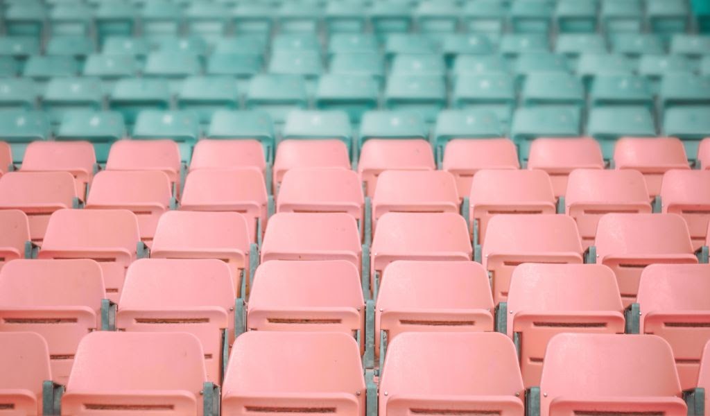 Řady růžových a zelených sedaček rozlišených dle sektorů na stadionu.